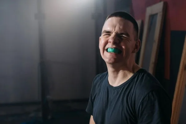 Illustrative service photograph of a person wearing a green sports mouthguard